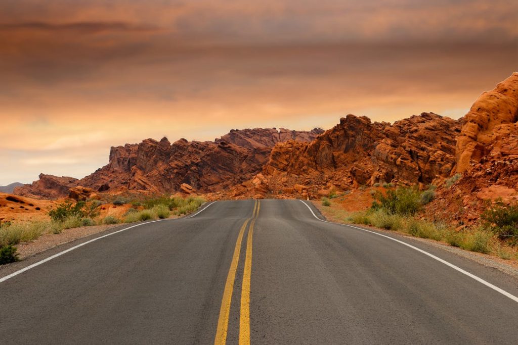 Gray asphalt road besides brown mountains